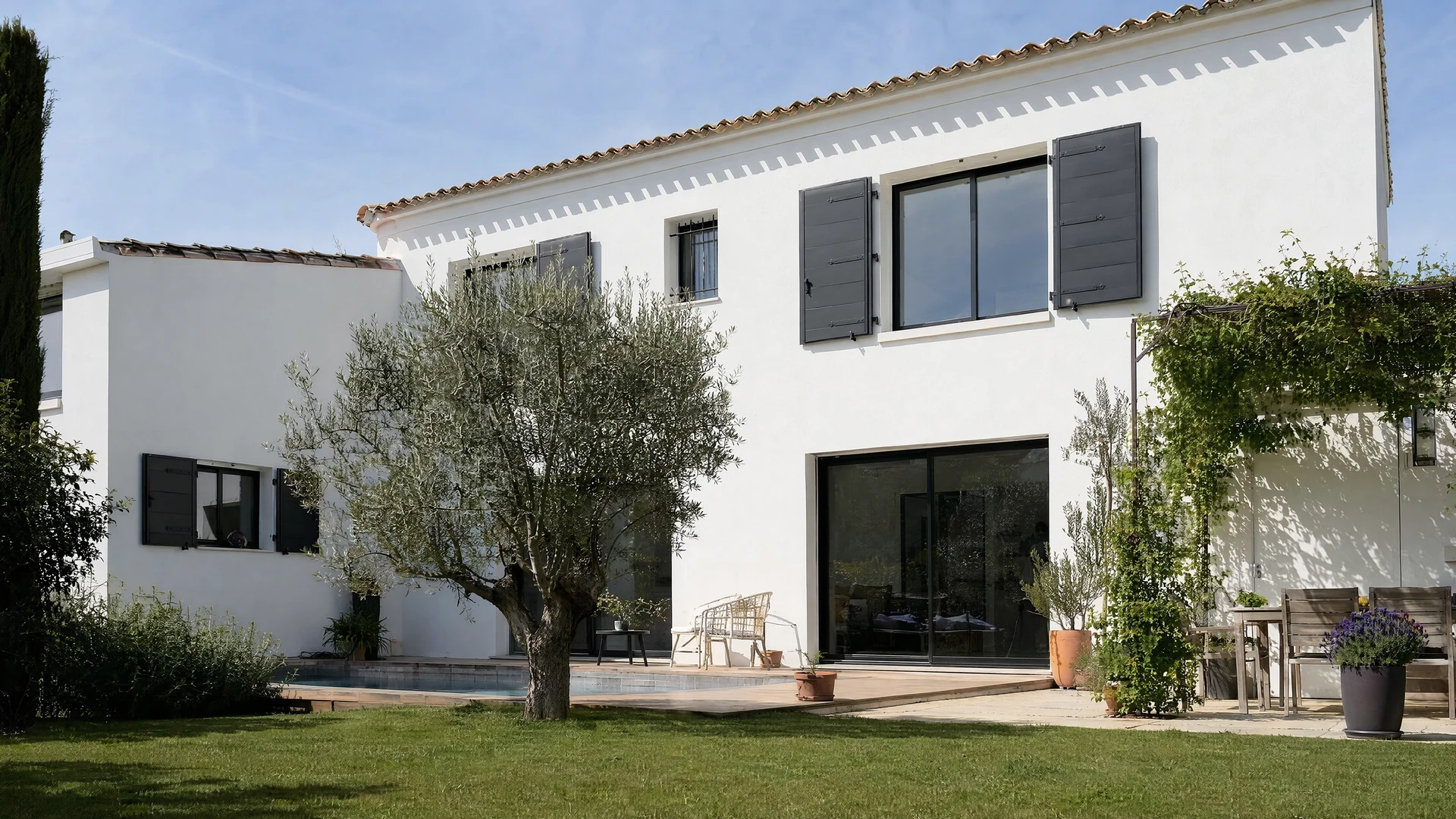 Mas provençal à deux étages, façade en enduit ocre rosé, volets bois vert sauge, toiture en tuiles canal